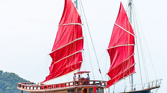 Junk boat with red sails at sunset off Koh Samui in December