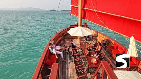 Traditional junk boat with red sails on turquoise water in the Gulf of Thailand